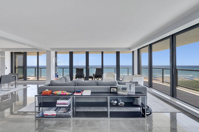 tiled living room featuring plenty of natural light, floor to ceiling windows, and a water view