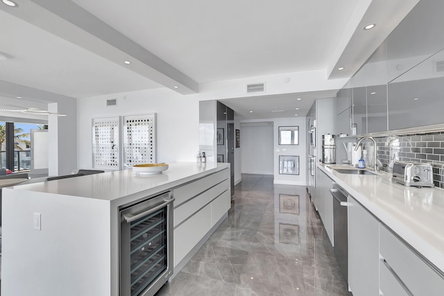 kitchen with beverage cooler, backsplash, tile flooring, sink, and a kitchen island