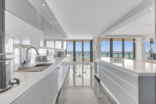 kitchen with a kitchen island, beverage cooler, tasteful backsplash, sink, and light tile floors