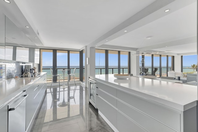 kitchen featuring expansive windows, a water view, a kitchen island, dishwasher, and tile flooring