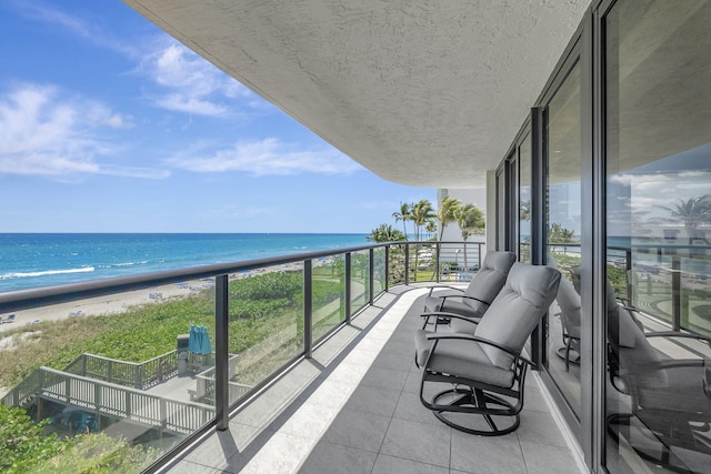 balcony featuring a view of the beach and a water view