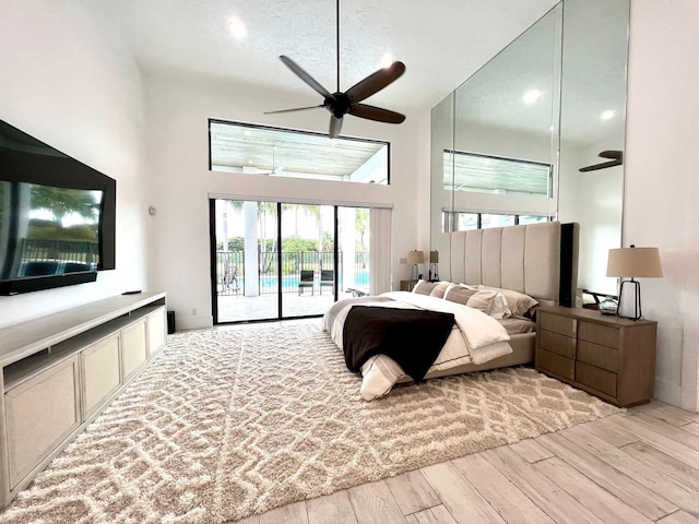 bedroom featuring ceiling fan, light wood-type flooring, a towering ceiling, and access to outside