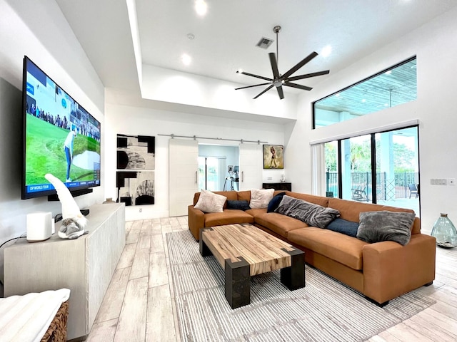 living room featuring a high ceiling, light hardwood / wood-style flooring, and ceiling fan