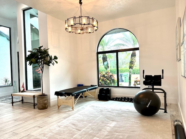 workout room featuring light hardwood / wood-style floors and a chandelier