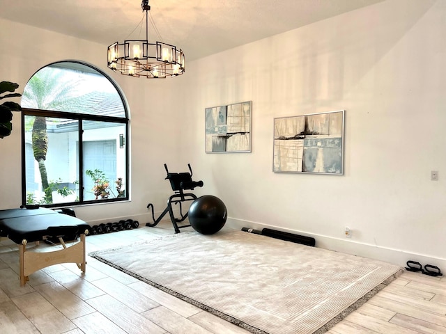 workout room with light hardwood / wood-style floors and a notable chandelier