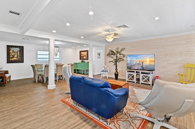 living room with a textured ceiling, ornate columns, ceiling fan, and crown molding