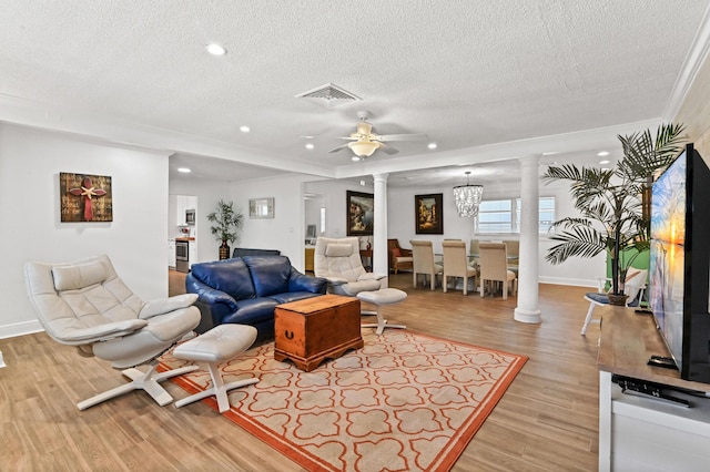 living room with ceiling fan with notable chandelier, a textured ceiling, light hardwood / wood-style floors, and ornamental molding