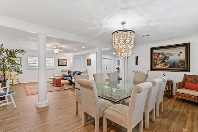 dining area featuring wood-type flooring, a textured ceiling, decorative columns, and ornamental molding