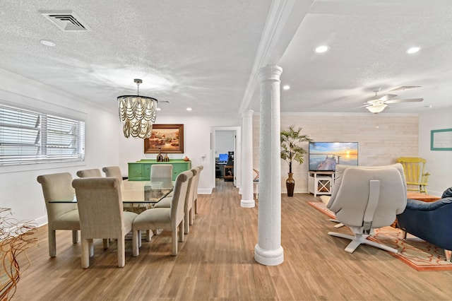 dining area with ornate columns, crown molding, a textured ceiling, and light wood-type flooring