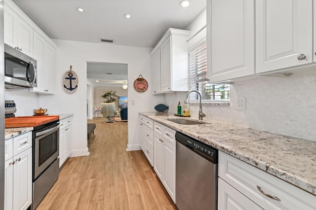 kitchen with sink, white cabinetry, stainless steel appliances, and light hardwood / wood-style flooring