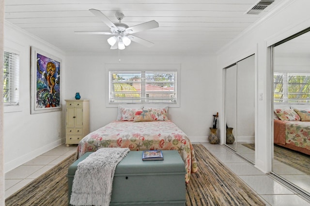 tiled bedroom featuring ceiling fan, wood ceiling, crown molding, and a closet