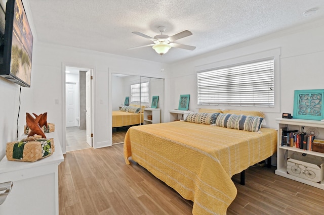 bedroom with hardwood / wood-style floors, a textured ceiling, a closet, and ceiling fan