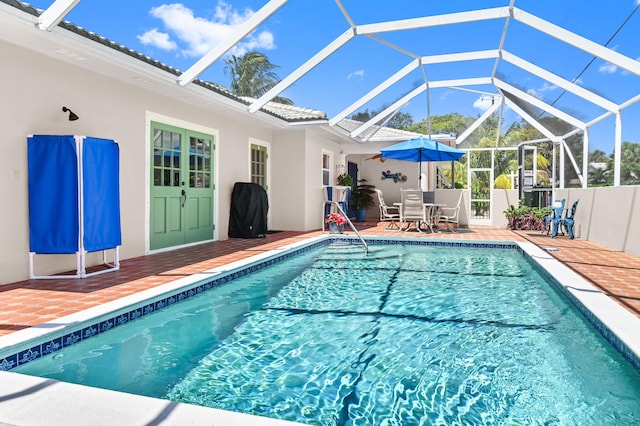 view of pool with glass enclosure and a patio area