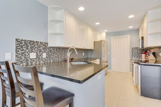 kitchen with tasteful backsplash, kitchen peninsula, a breakfast bar, and white cabinetry