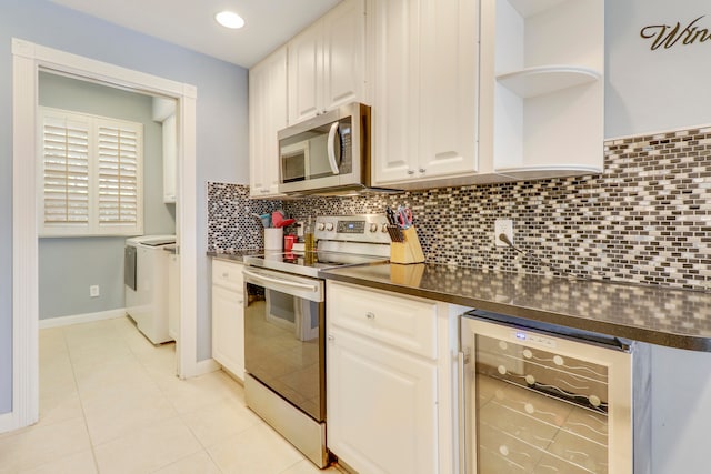 kitchen featuring wine cooler, washer and clothes dryer, white cabinetry, backsplash, and stainless steel appliances