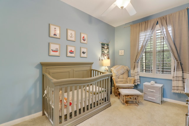 carpeted bedroom with ceiling fan and a crib