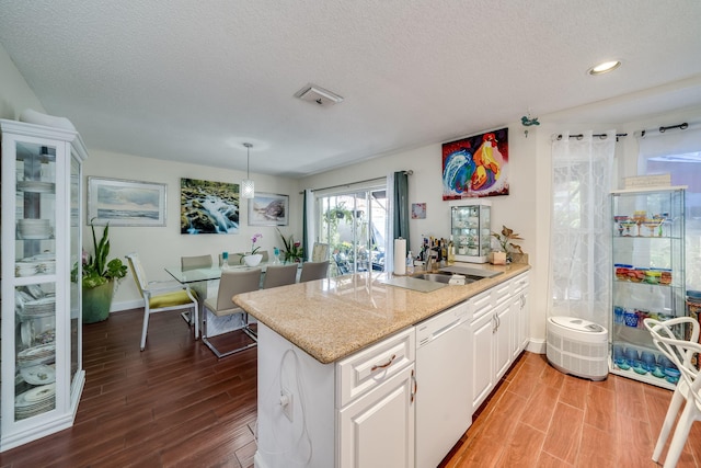 kitchen with light hardwood / wood-style floors, a textured ceiling, dishwasher, and white cabinets