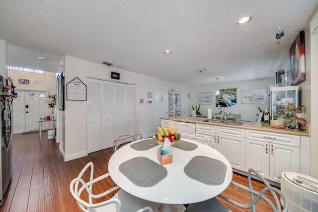 dining room with sink, a textured ceiling, and dark hardwood / wood-style flooring