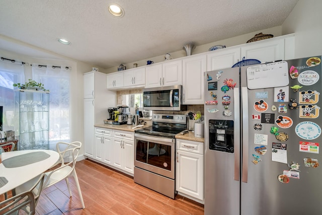 kitchen with white cabinetry, stainless steel appliances, and light wood-type flooring