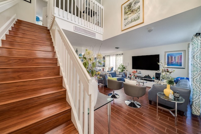 staircase featuring a towering ceiling and hardwood / wood-style floors