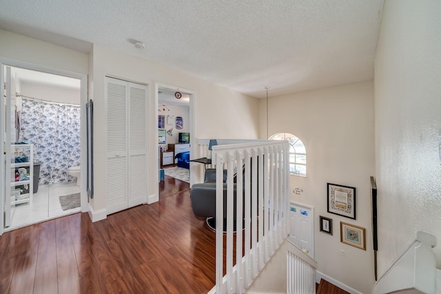 hallway with a textured ceiling and dark wood-type flooring