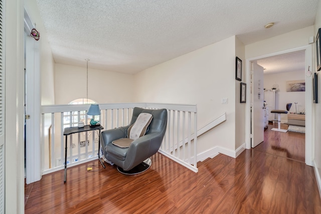 living area with a textured ceiling, baseboard heating, and dark wood-type flooring