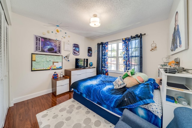 bedroom with a closet, a textured ceiling, and dark hardwood / wood-style floors