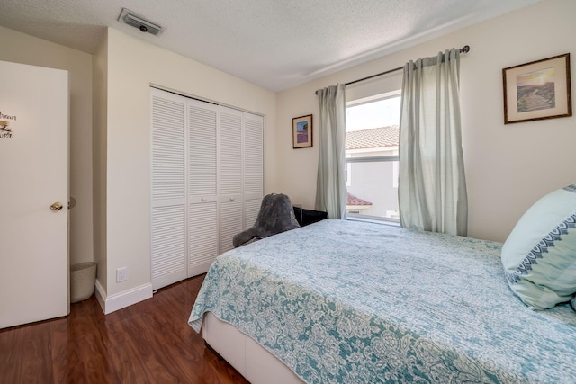 bedroom with a closet, dark hardwood / wood-style floors, and a textured ceiling