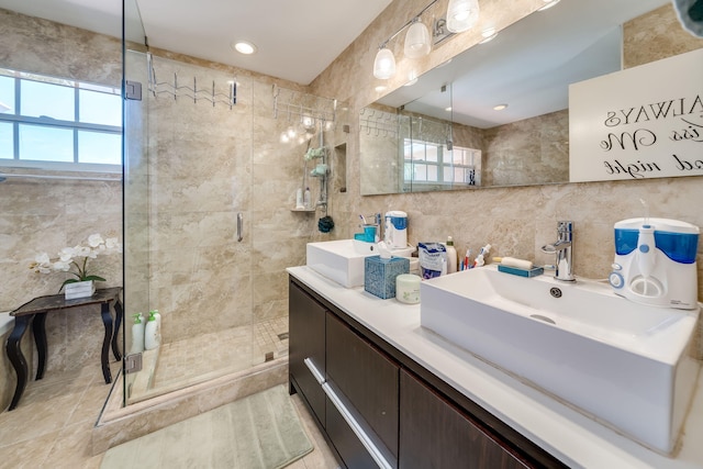 bathroom featuring vanity, a healthy amount of sunlight, tile walls, and a shower with shower door