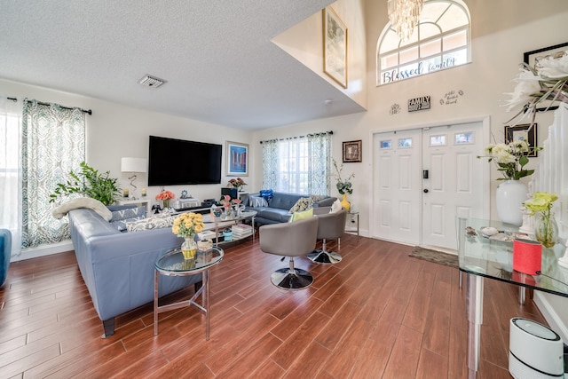 living room featuring hardwood / wood-style floors, a textured ceiling, and a towering ceiling