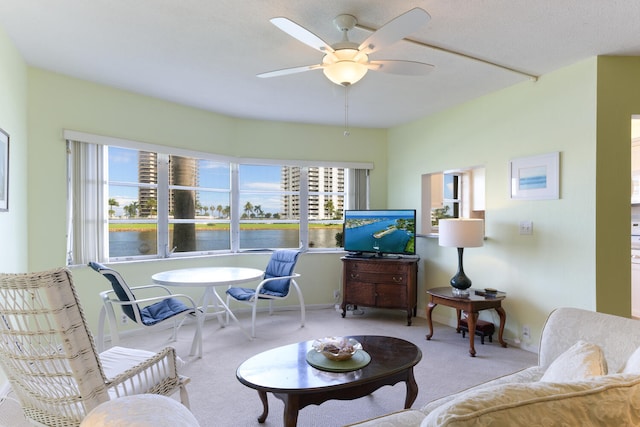 living room featuring ceiling fan, carpet floors, and a water view