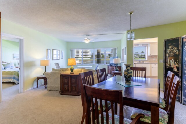 carpeted dining area with sink, ceiling fan, and a textured ceiling