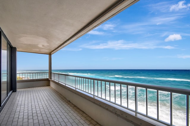 balcony with a water view and a view of the beach