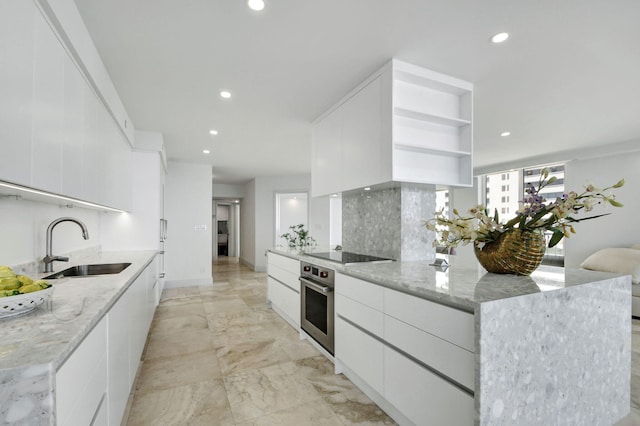 kitchen with white cabinets, oven, and light stone countertops