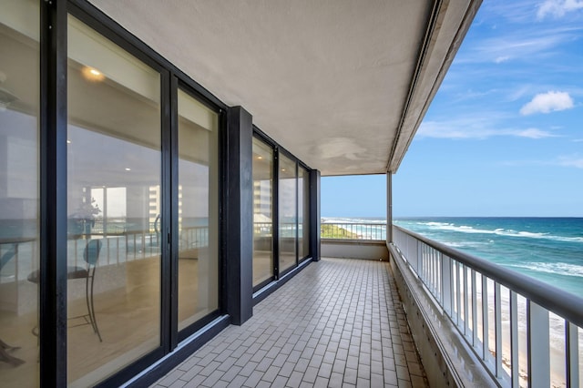 balcony with a water view and a view of the beach