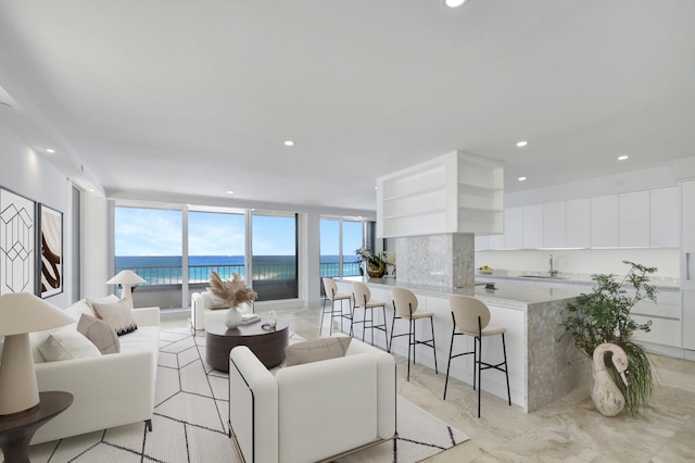 living room with sink, a water view, and a wall of windows