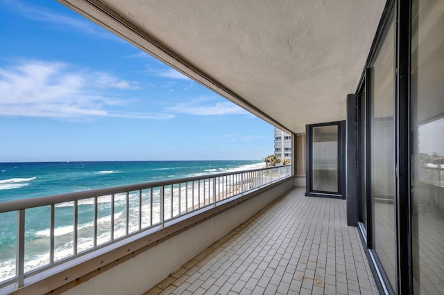 balcony with a water view and a view of the beach