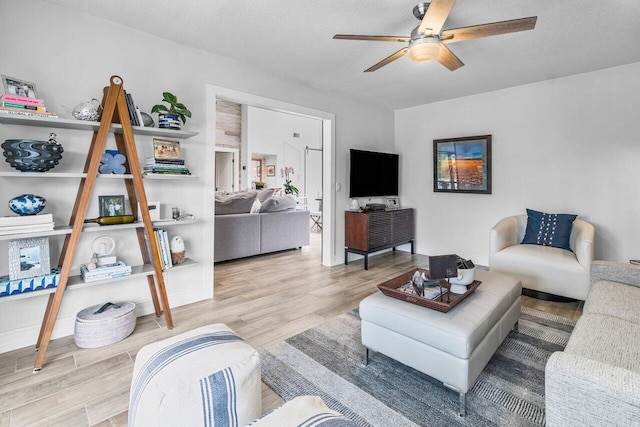 living room featuring hardwood / wood-style floors, ceiling fan, and a textured ceiling