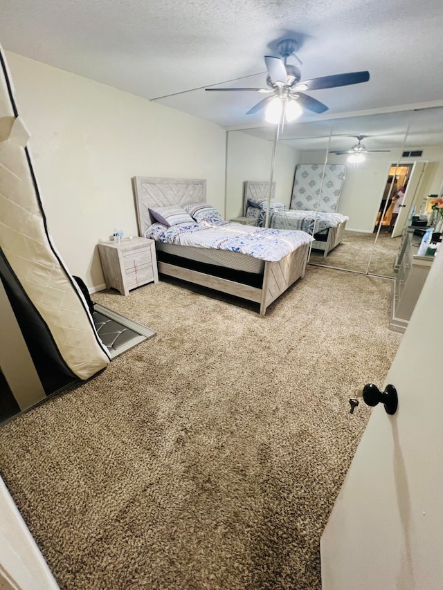 carpeted bedroom with ceiling fan and a textured ceiling