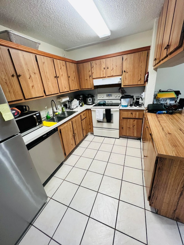 kitchen featuring a textured ceiling, sink, stainless steel appliances, and light tile floors