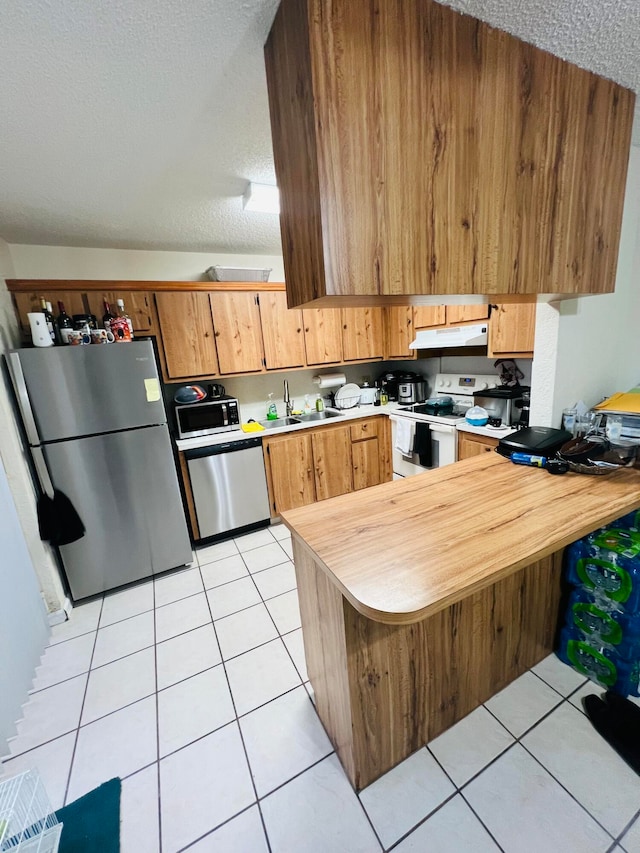 kitchen with kitchen peninsula, appliances with stainless steel finishes, a textured ceiling, and light tile floors