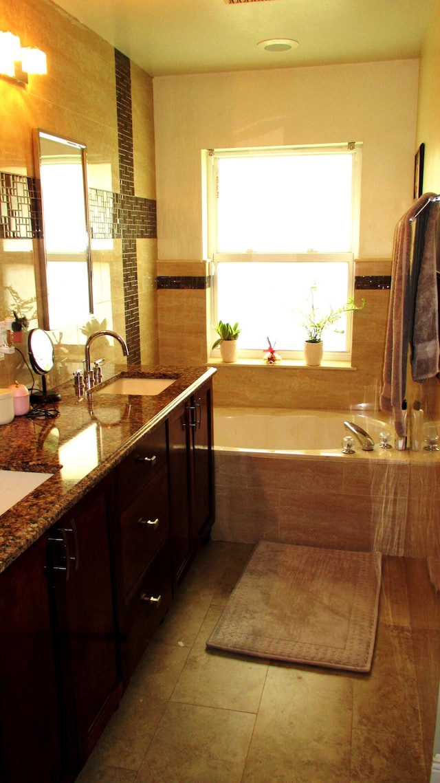 bathroom with a relaxing tiled bath, dual bowl vanity, and tile flooring