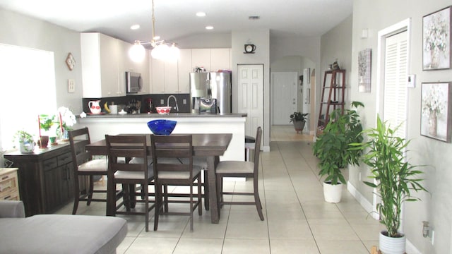 kitchen featuring kitchen peninsula, appliances with stainless steel finishes, white cabinets, and light tile flooring