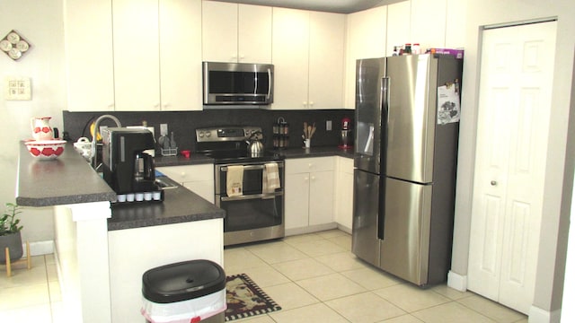 kitchen with backsplash, kitchen peninsula, appliances with stainless steel finishes, and light tile floors