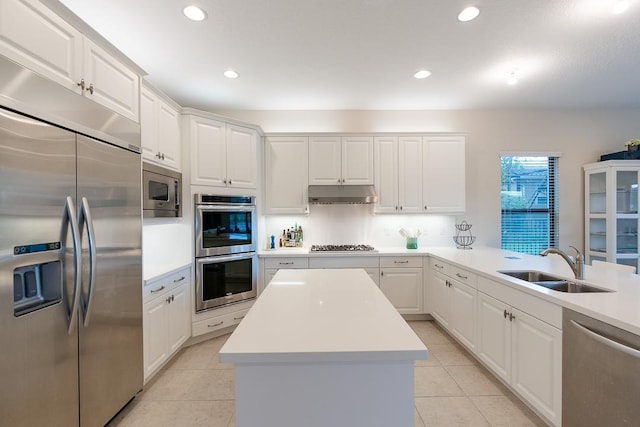 kitchen with light tile patterned flooring, built in appliances, sink, and white cabinetry