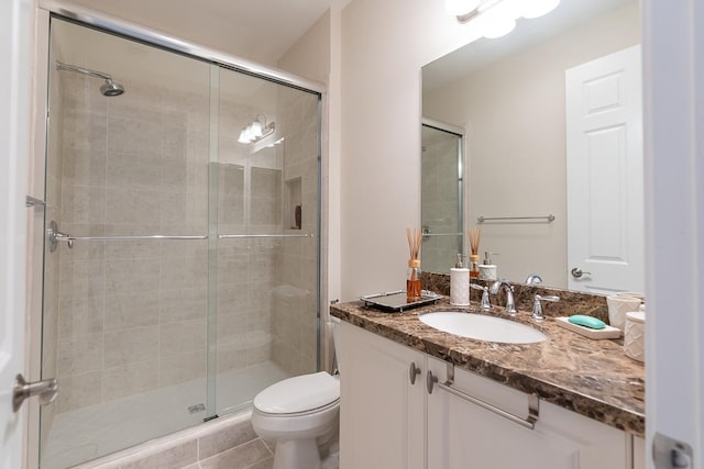 bathroom with vanity, walk in shower, tile patterned flooring, and toilet