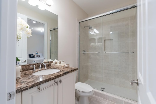 bathroom with a shower with door, vanity, tile patterned flooring, and toilet