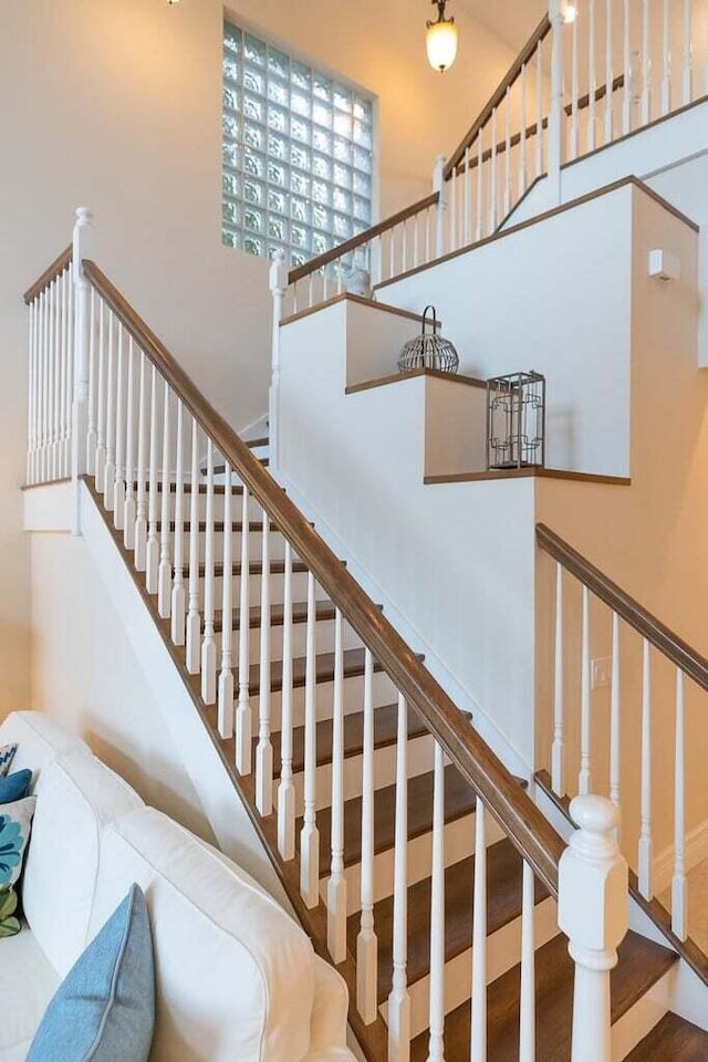 staircase featuring wood-type flooring and a towering ceiling