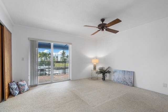 unfurnished room with a textured ceiling, ceiling fan, ornamental molding, and carpet