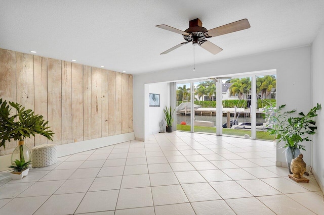 tiled spare room with ceiling fan and wooden walls